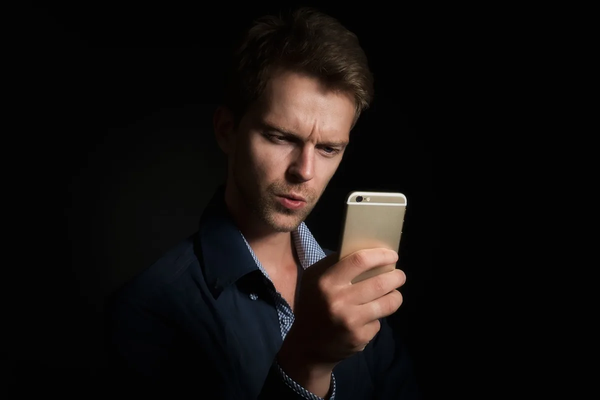 Personne consultant des alertes de solde sur un smartphone près d'une fenêtre en plein jour