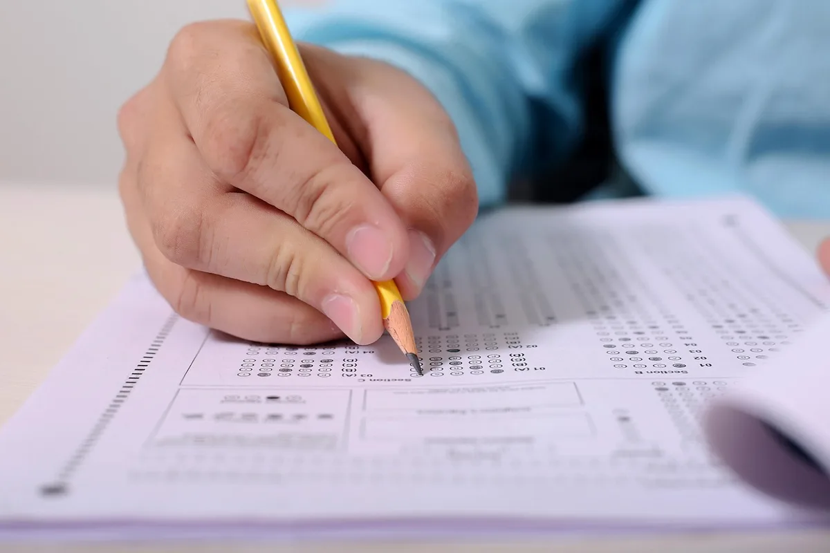 Personne anonyme parcourant une page web sur un écran flou, prises de notes sur un carnet