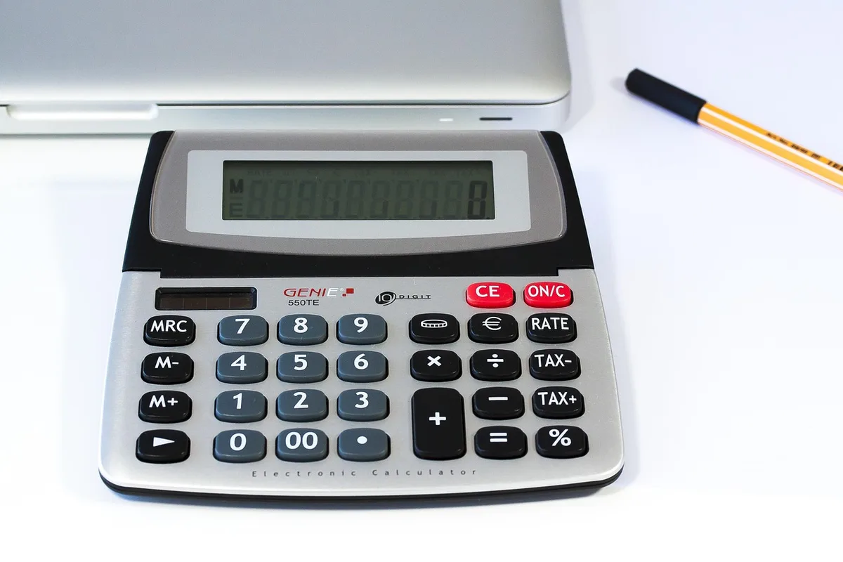 Personne calculant son budget mensuel avec une calculatrice et des notes