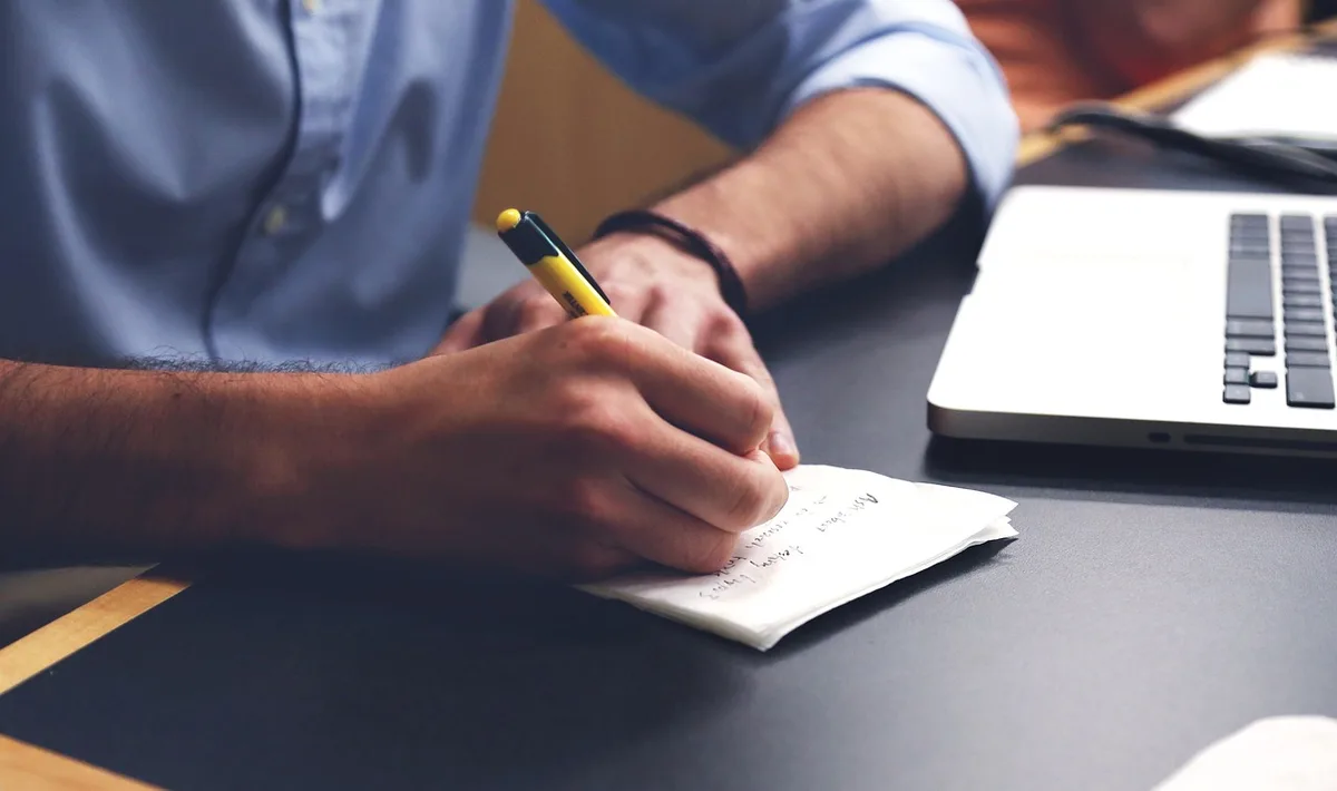 Rédaction d'un CV sur un bureau avec stylo, documents et ordinateur portable