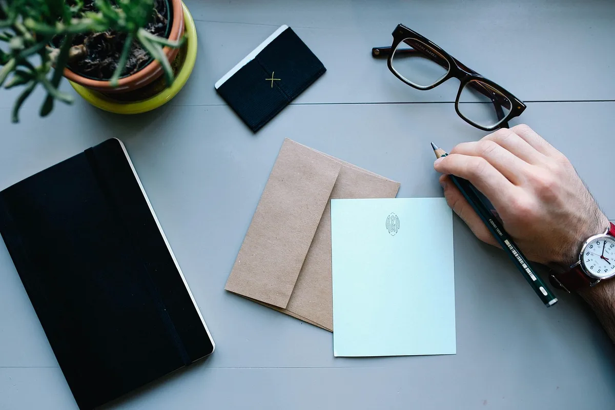 Main écrivant des notes commerciales à côté d'un ordinateur