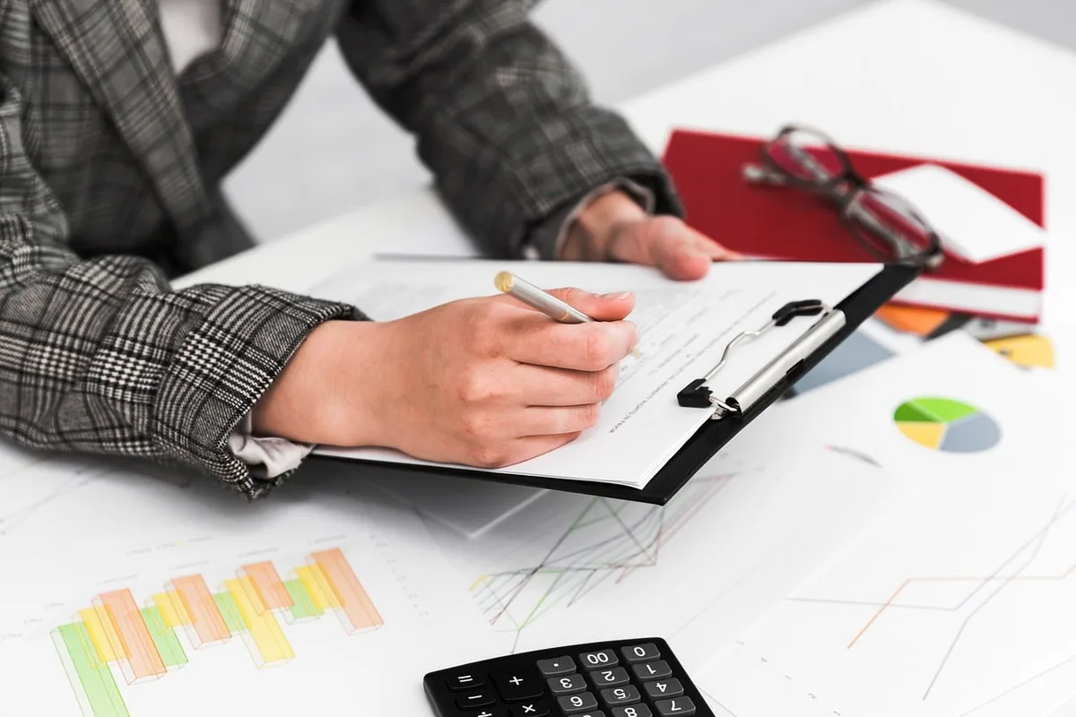 Main vérifiant des documents de prêt et une calculatrice sur une table en journée