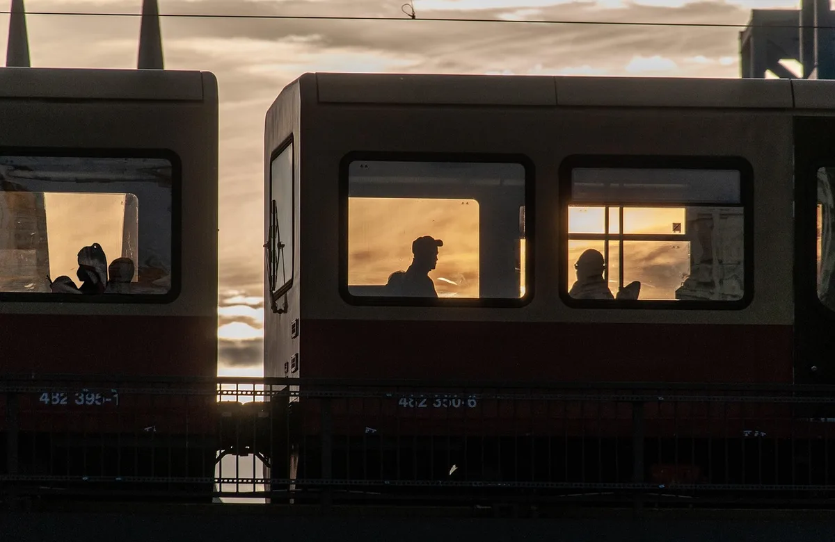 Passagers anonymes installés dans un wagon de train moderne, fenêtres laissant entrer la lumière